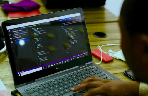A person analyzing scam scripts and email fraud code on a laptop, illustrating the techniques used in Nigerian scams